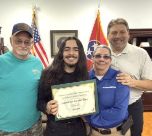 Four individuals pose for a photo; one holds a "Tennessee Sheriffs' Association Certificate of Scholarship" for Lazuras Easterling for $500.00 in 2026. The Tennessee and US flags are visible in the background.