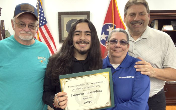 Four individuals pose for a photo; one holds a "Tennessee Sheriffs' Association Certificate of Scholarship" for Lazuras Easterling for $500.00 in 2026. The Tennessee and US flags are visible in the background.