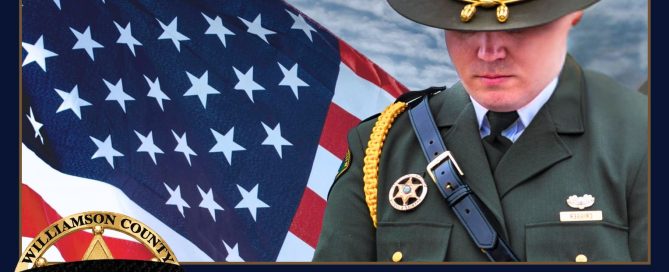 A Williamson County Sheriff’s Office deputy stands in ceremonial uniform with head bowed in front of a large American flag under a cloudy sky. A black mourning band is displayed across the Sheriff’s Office badge in the lower corner. The graphic reads: “Peace Officers Memorial Day, May 15th, 2026, Honoring the Fallen, Remembering Their Sacrifice.” The image honors law enforcement officers who lost their lives in the line of duty.