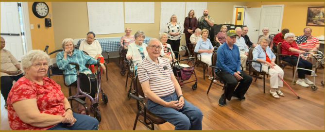 A group of senior residents sits in a community room during a public safety presentation. Three Members of the Williamson County Sheriff’s Office stand at the back of the room while attendees face the camera.