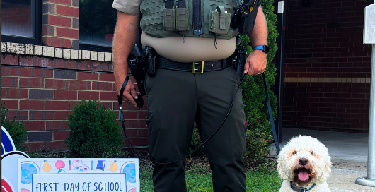 Sergeant Morley and K9 Bolo pose for a first day of school photo at campus. K9 Bolo, a police dog assigned to school duty, sits beside Sergeant Morley as they help welcome students back for the new school year.