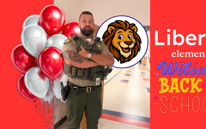 WCSO SRO Deputy Anglin stands with his arms crossed in a hallway at Liberty Elementary School. The graphic features red and silver balloons, the Liberty Elementary lion mascot, and colorful “Welcome Back to School” artwork on a bright red background.