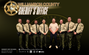 Seven uniformed deputies stand alongside a man in a tan polo shirt. The graphic features a gold badge, the heading “Williamson County Sheriff’s Office” and a faint Office emblem on a dark olive and black background. The footer reads “Sheriff Jeff Hughes” and includes 408 Century Court, Franklin, TN 37064; WilliamsonCountySheriffTN.com; and social media icons.