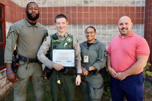 Deputy Harper stands with three colleagues outside the Williamson County Sheriff’s Office detention facility, holding a framed Certificate of Appreciation recognizing him as the September Employee of the Month.