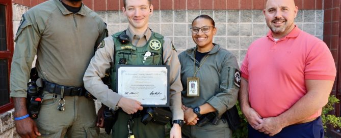 Deputy Harper stands with three colleagues outside the Williamson County Sheriff’s Office detention facility, holding a framed Certificate of Appreciation recognizing him as the September Employee of the Month.